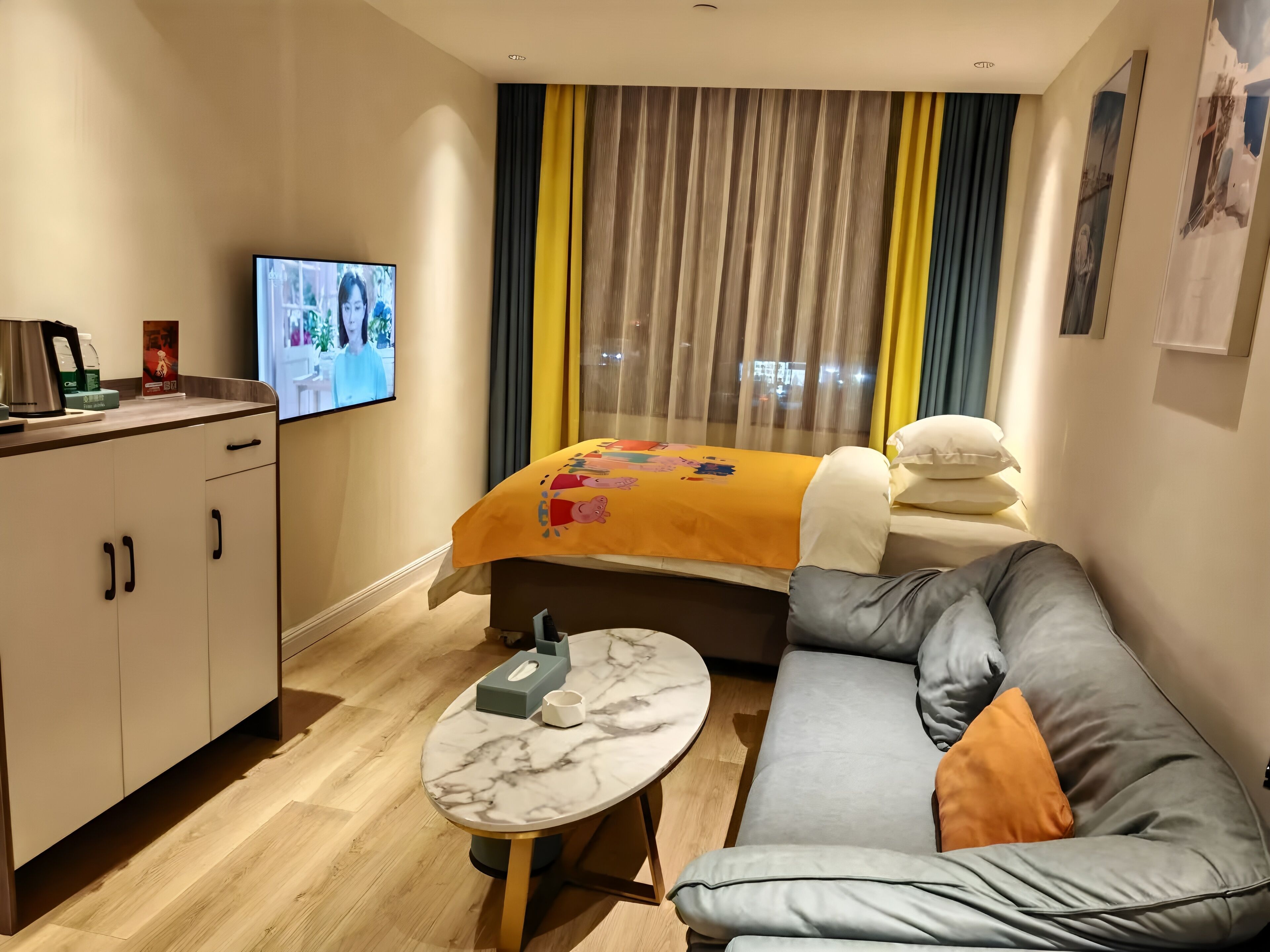 A modern hotel room with a bed, sofa, and a small table.