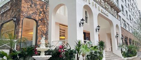 A hotel with a stone facade, a fountain, and a pool area.