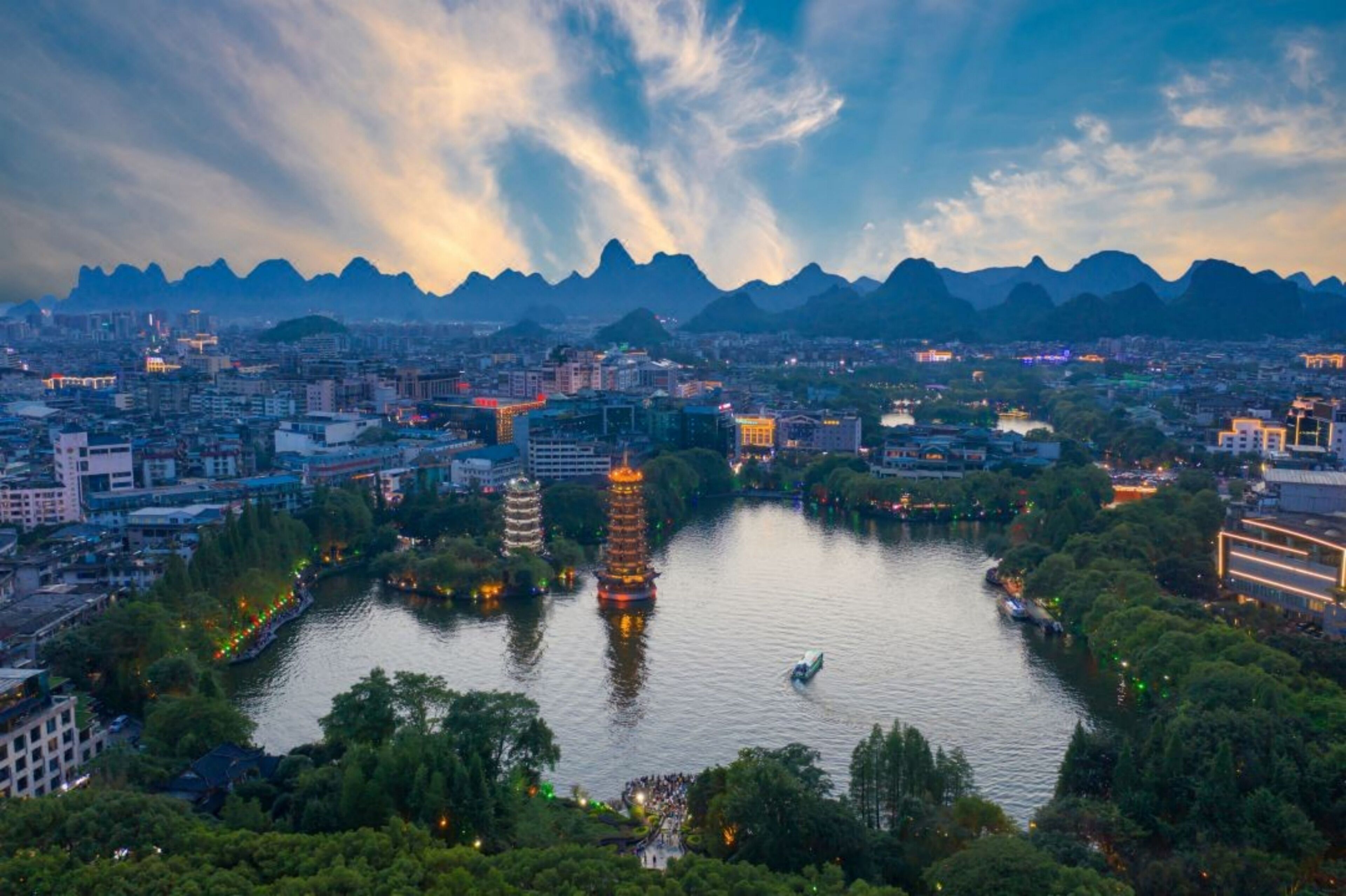 A cityscape with a river, pagodas, and mountains in the background.