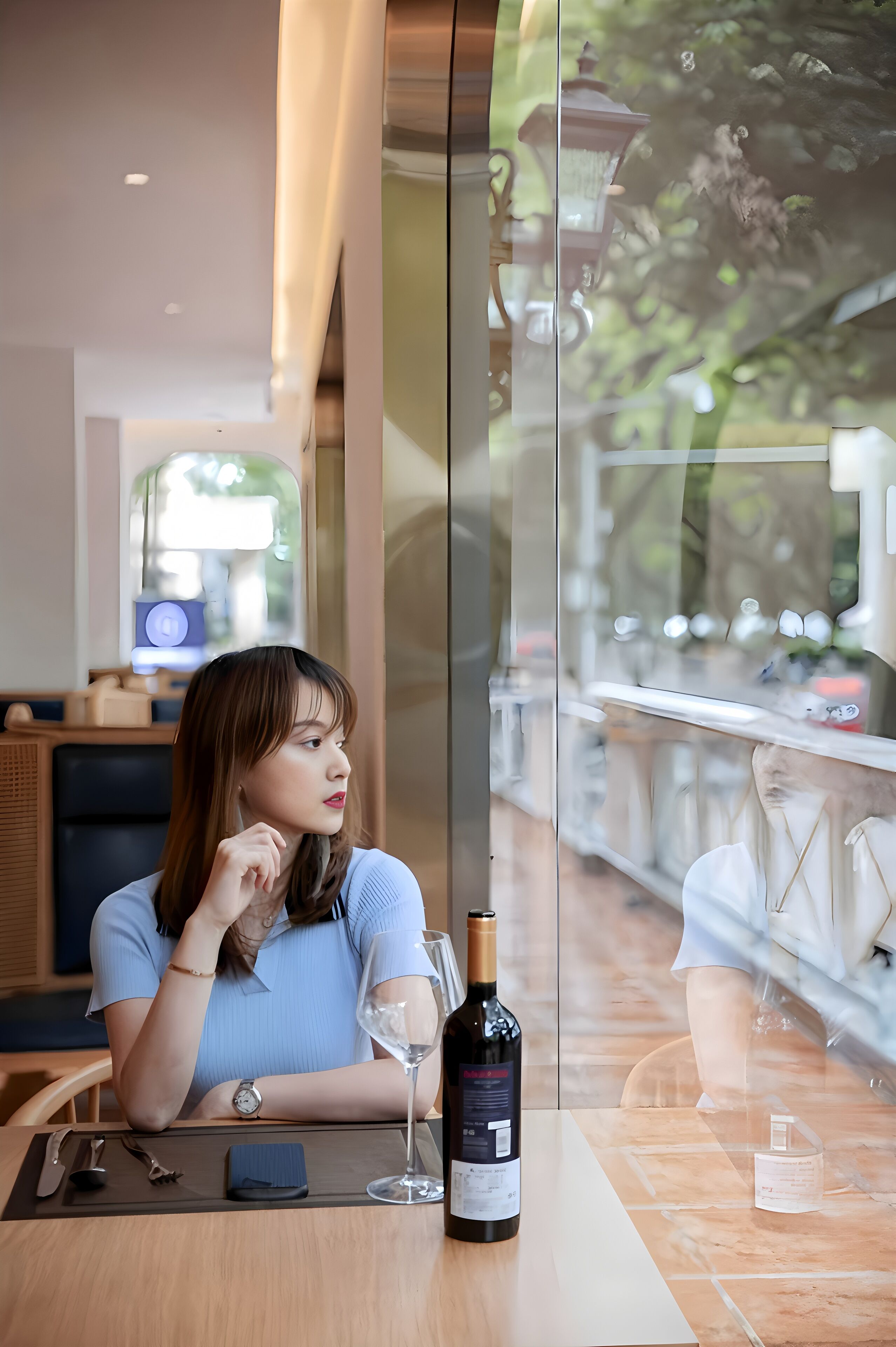 A woman sitting at a table with a wine bottle and glass, a watch, and a menu.