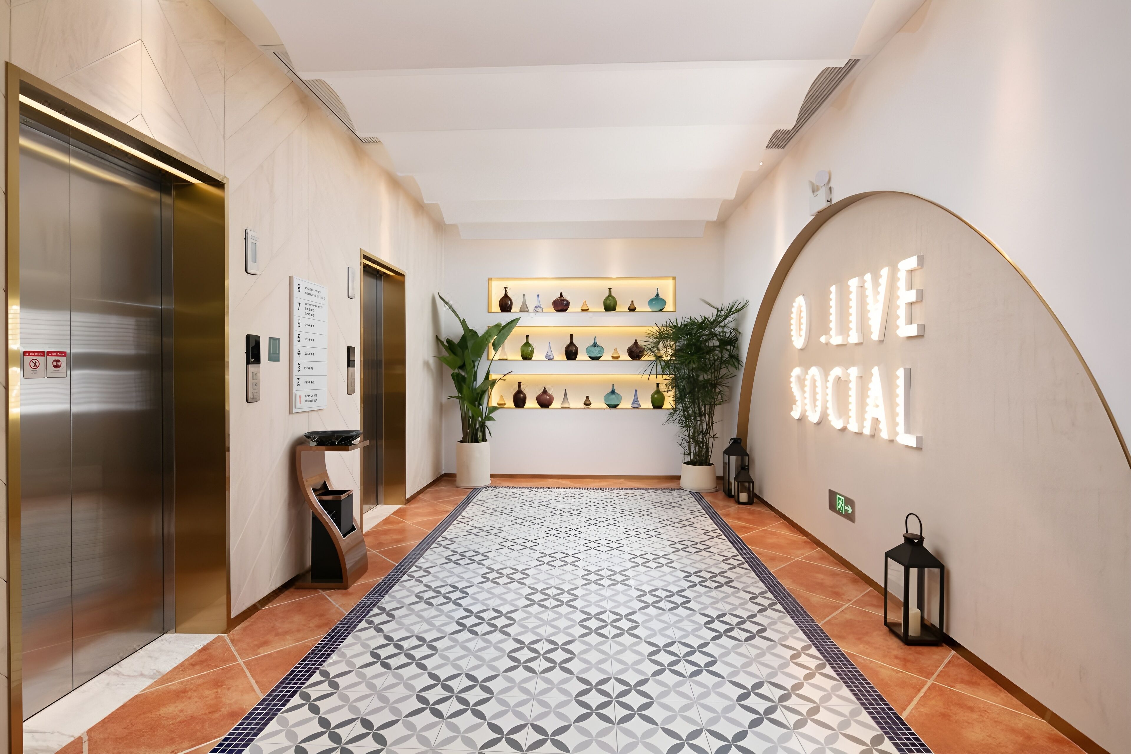 Un hall de hotel con suelo estampado, una recepción, una exposición de jarrones en la pared y un ascensor.