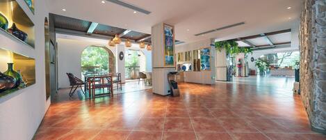 A spacious lobby with a tiled floor, a reception desk, and a seating area with chairs.