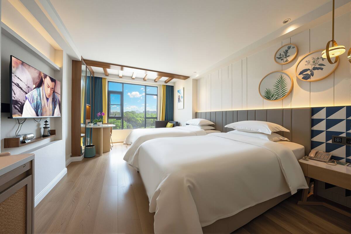 Quarto de hotel moderno com duas camas, televisão, escrivaninha e vista para o exterior.