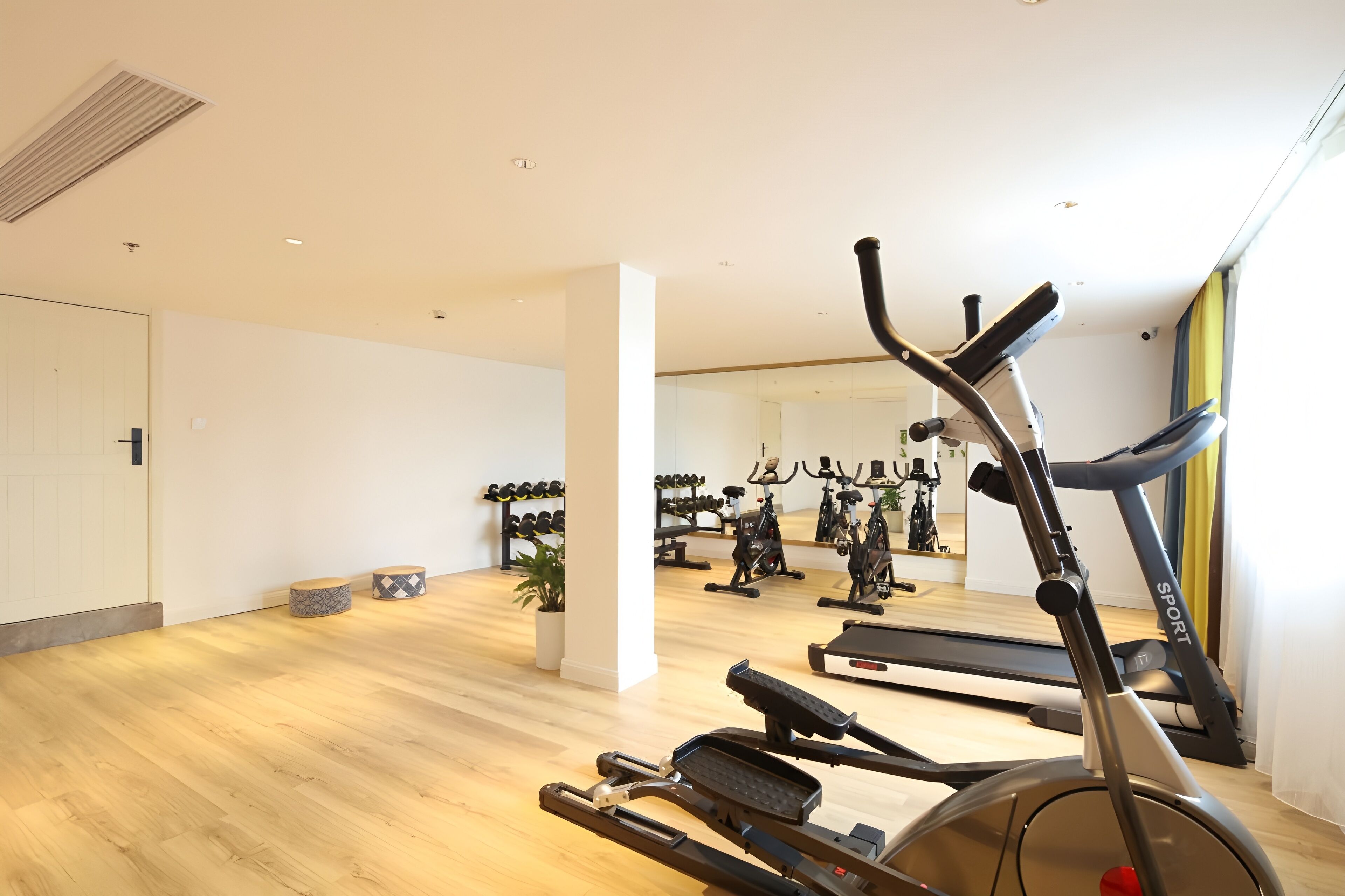 A gym with treadmills, stationary bikes, and dumbbells.