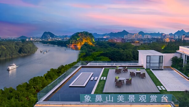 A rooftop terrace with outdoor seating, overlooking a river and cityscape. - Guilin O-LIVE Social Hotel  (Guilin)