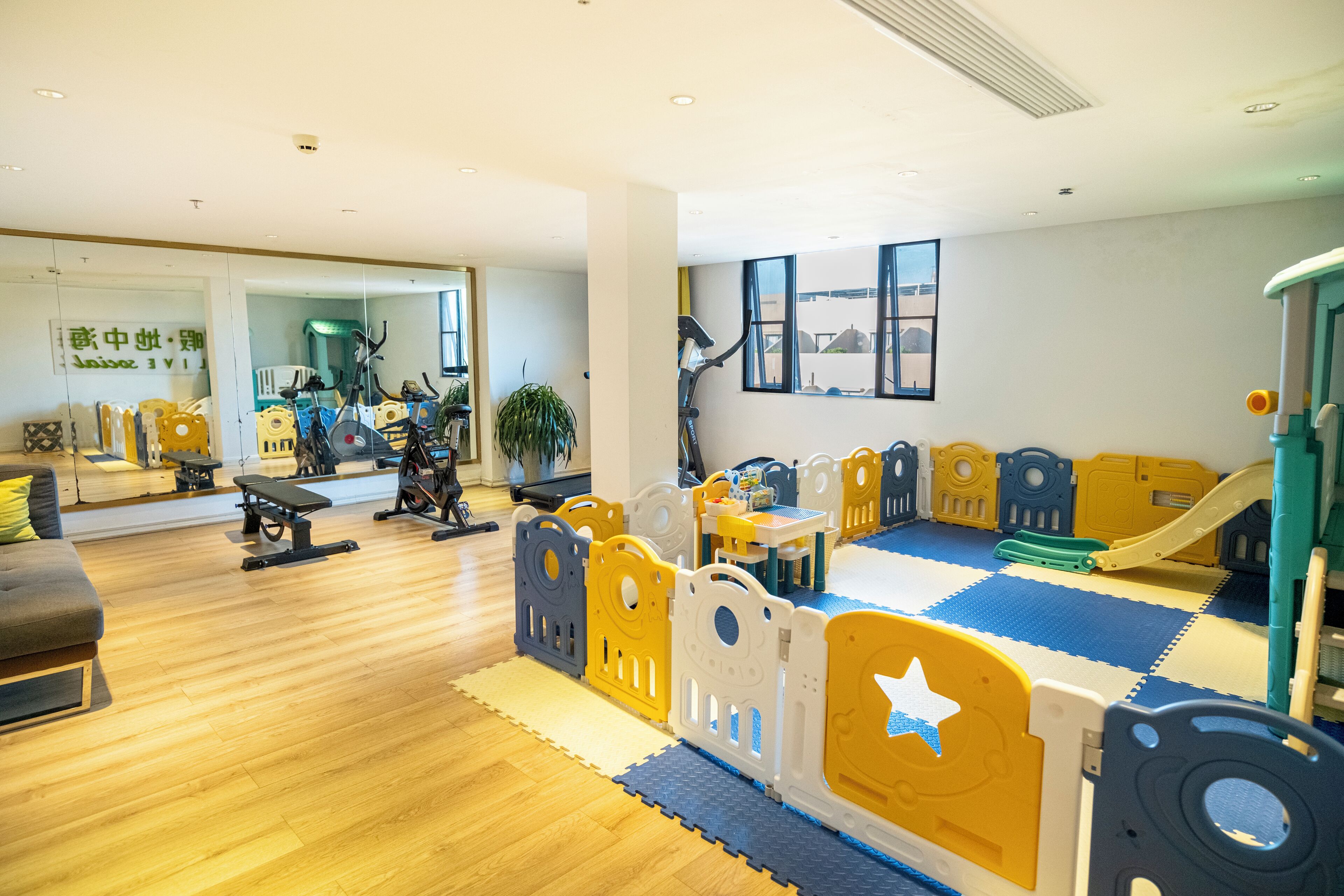 Un espace de jeux pour enfants avec des structures de jeu rembourrées, un toboggan et du matériel d’exercice.
