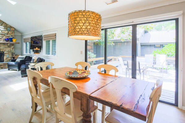 A dining area with a wooden table and chairs, a decorative bowl, and a hanging light fixture.
