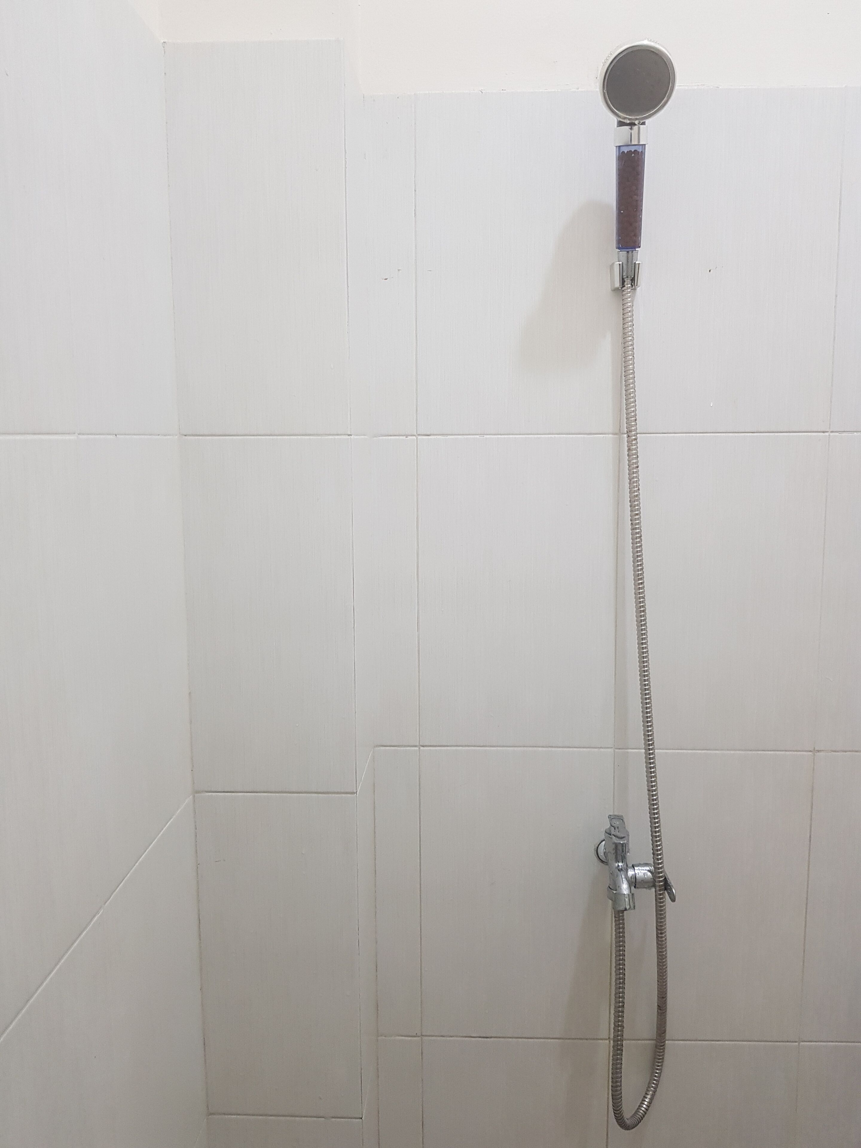Chuveiro com chuveiro manual e mangueira flexível.