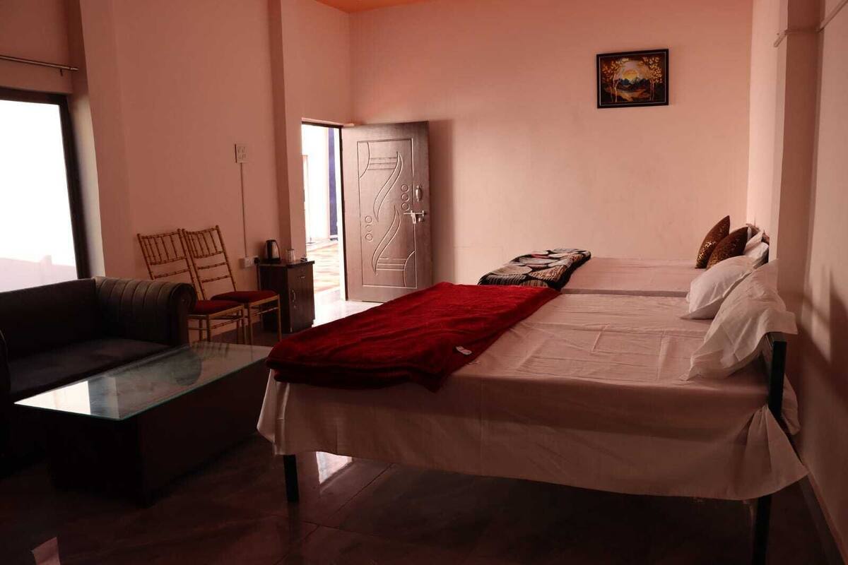 A bedroom with a bed, a red blanket, a sofa, and a chair.