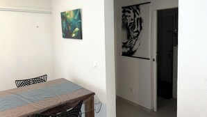 Ein Essbereich mit Holztisch und -stühlen, einem Bild von tropischen Blättern und einem Wandgemälde mit einem Tiger.