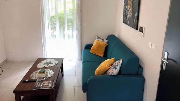 Ein Wohnzimmer mit einem türkisfarbenen Sofa, einem Couchtisch und einem Gemälde an der Wand.