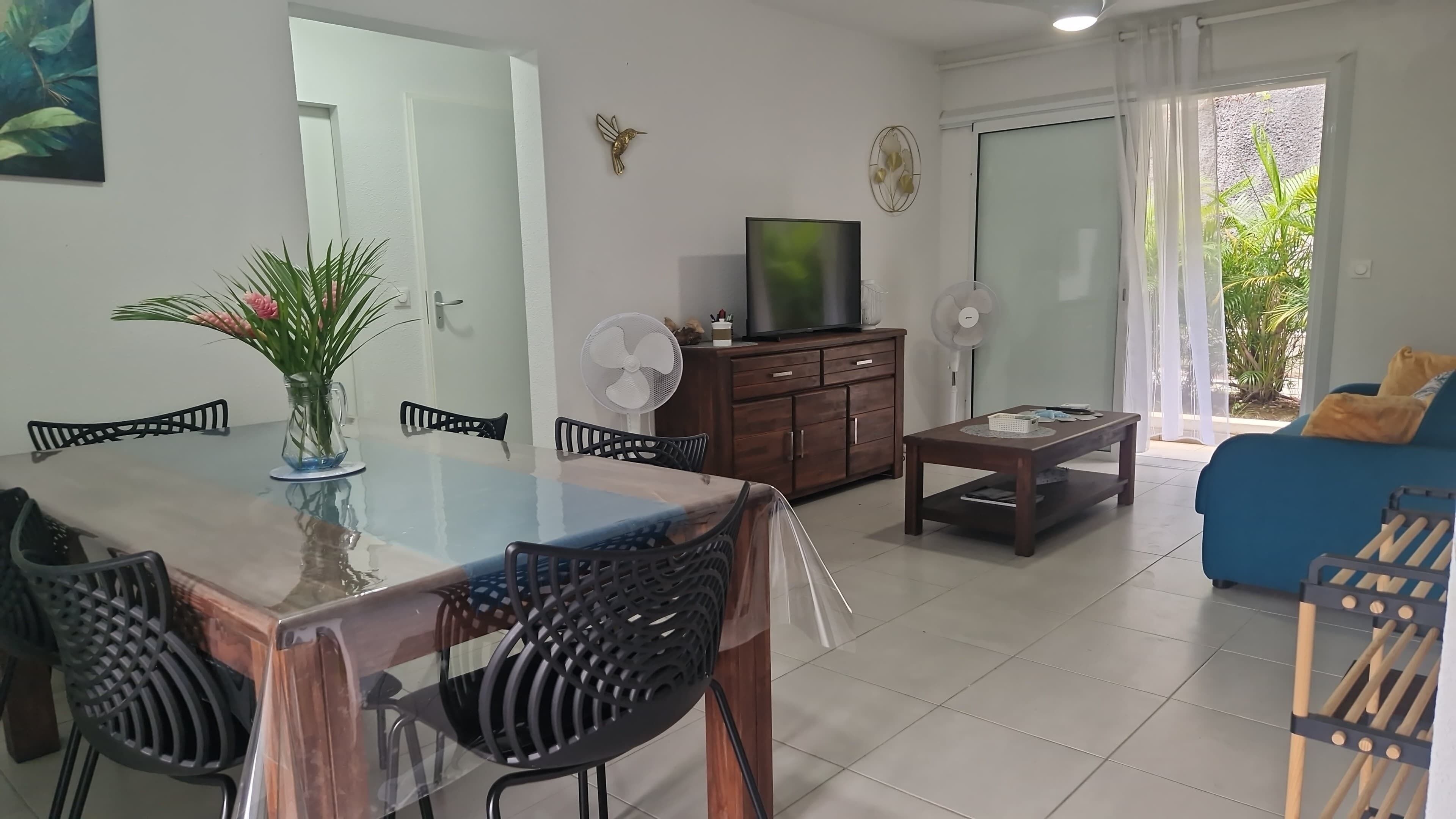 A modern living room with a dining area, a TV, and a sofa.