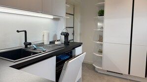 Een moderne keuken met een zwart aanrecht, witte kastjes en een inbouw vaatwasser.