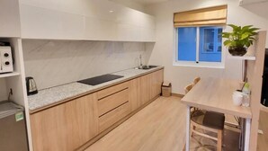 A modern kitchen with wooden cabinets, a built-in oven, and a window with a view. - Simmi 4 Hotel & Apartment Near SECC (Ho Chi Minh City)