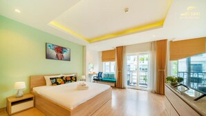 A modern hotel room with a large bed, a small desk, a seating area with a view, and a balcony. - Simmi 4 Hotel & Apartment Near SECC (Ho Chi Minh City)