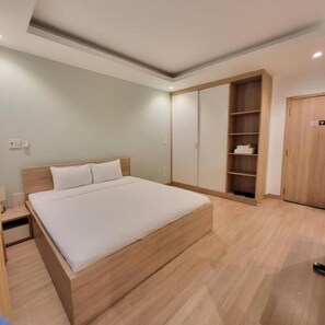 A bedroom with a large bed, wooden wardrobe, and built-in shelving. - Simmi 4 Hotel & Apartment Near SECC (Ho Chi Minh City)
