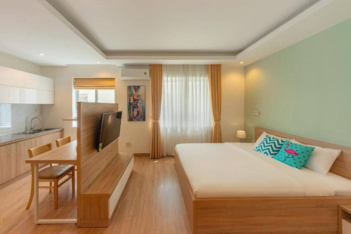 Ein Hotelzimmer mit Bett, Schreibtisch, Stuhl, Fernseher und einem Fenster mit Vorhängen.