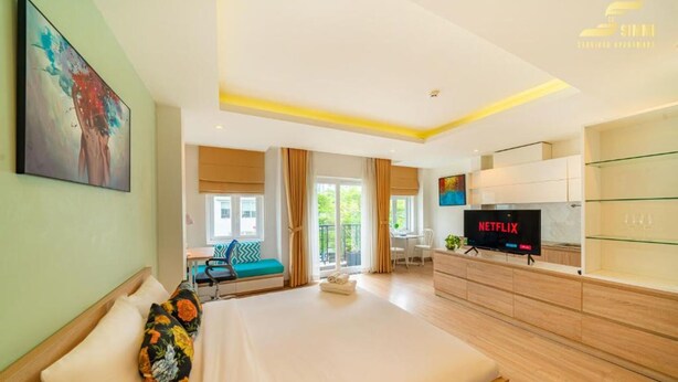 A modern hotel room with a large bed, a desk, a television, and a balcony with a view. - Simmi 4 Hotel & Apartment Near SECC (Ho Chi Minh City)