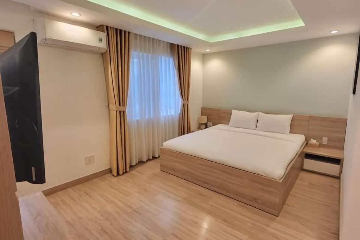 Ein modernes Hotelzimmer mit einem großen Bett, einem Holzkopfstück, Nachttischen und einer Klimaanlage.