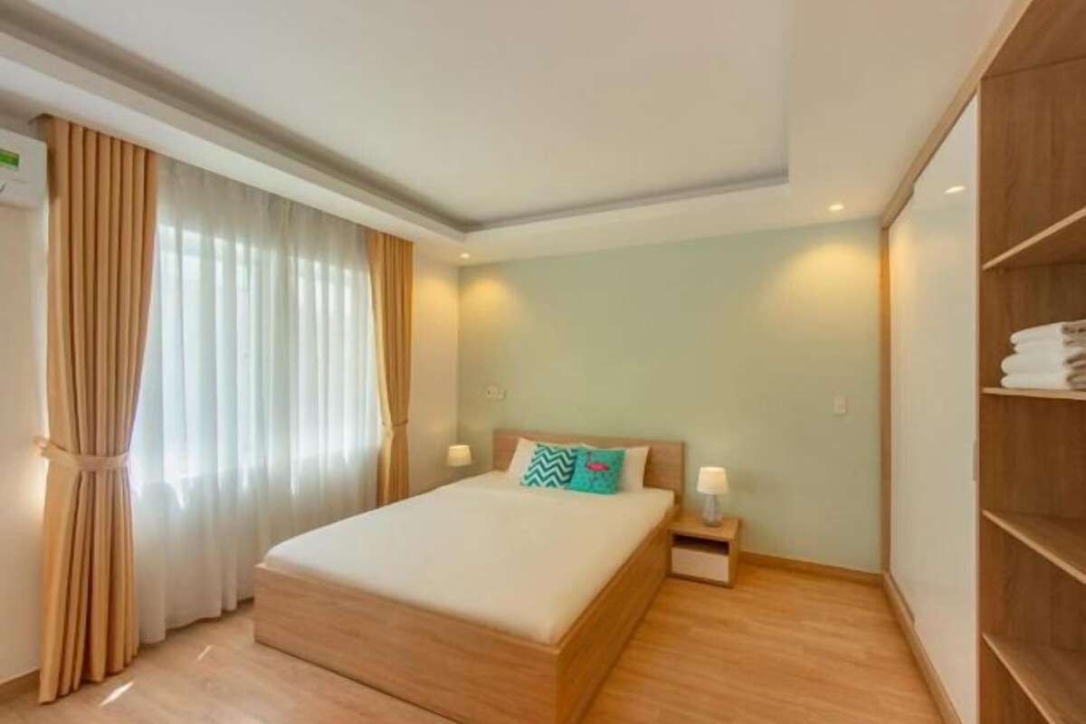 A neatly arranged bedroom with a bed, bedside tables, and a wardrobe.