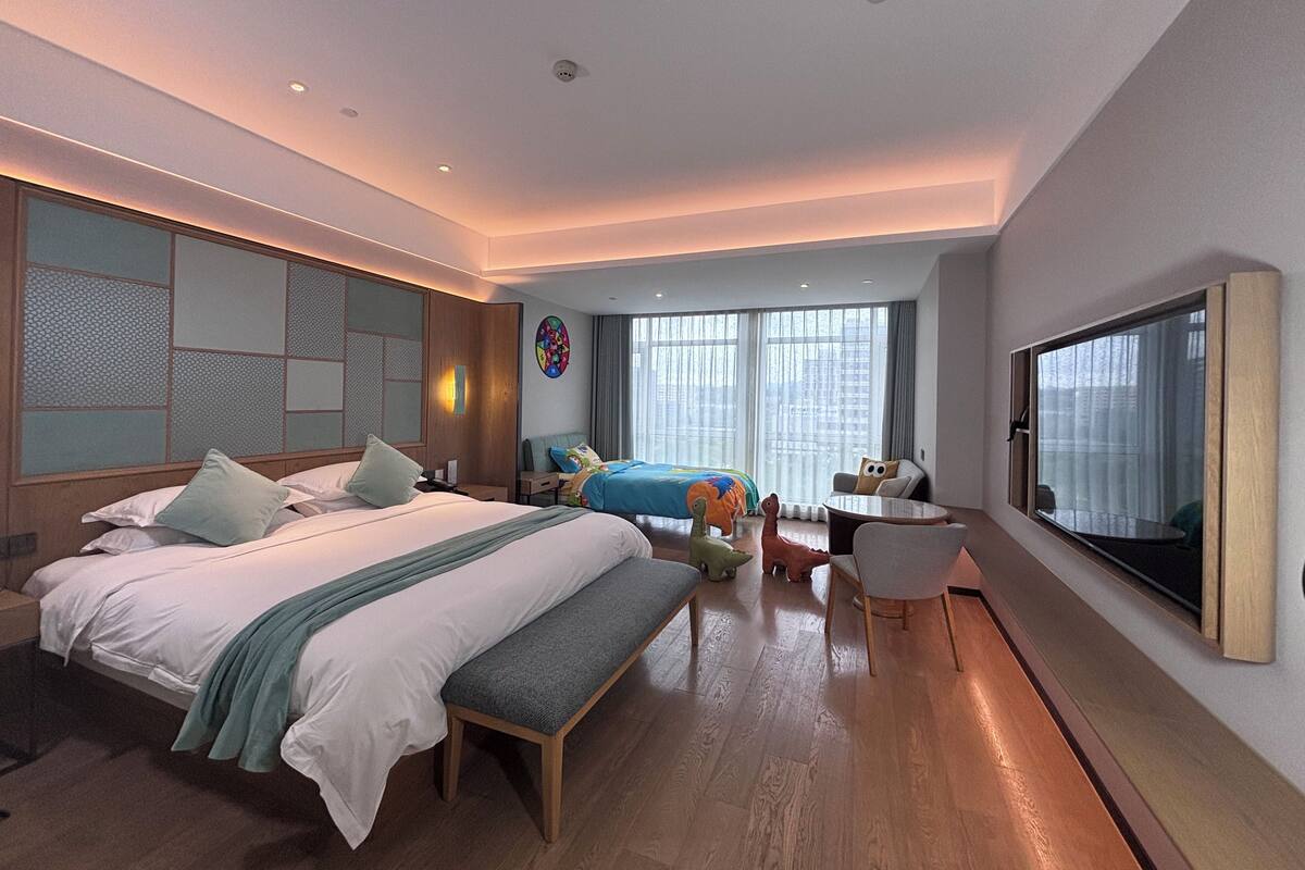 Una habitación de hotel moderna con una cama grande, un escritorio, una silla y un televisor.