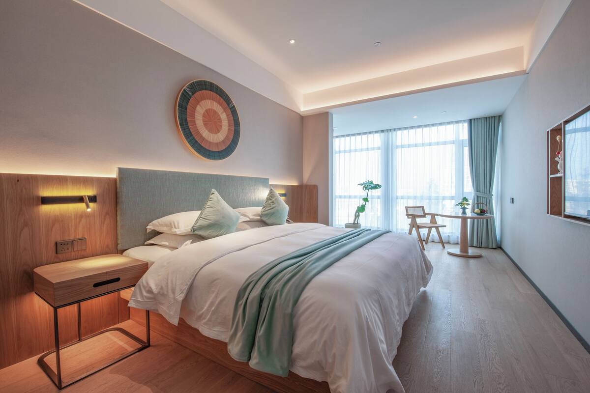 Una habitación de hotel moderna con una cama grande, una mesita de noche y un pequeño escritorio con una silla.