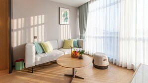 Un salon moderne avec un canapé, une table basse ronde et une petite table d’appoint.