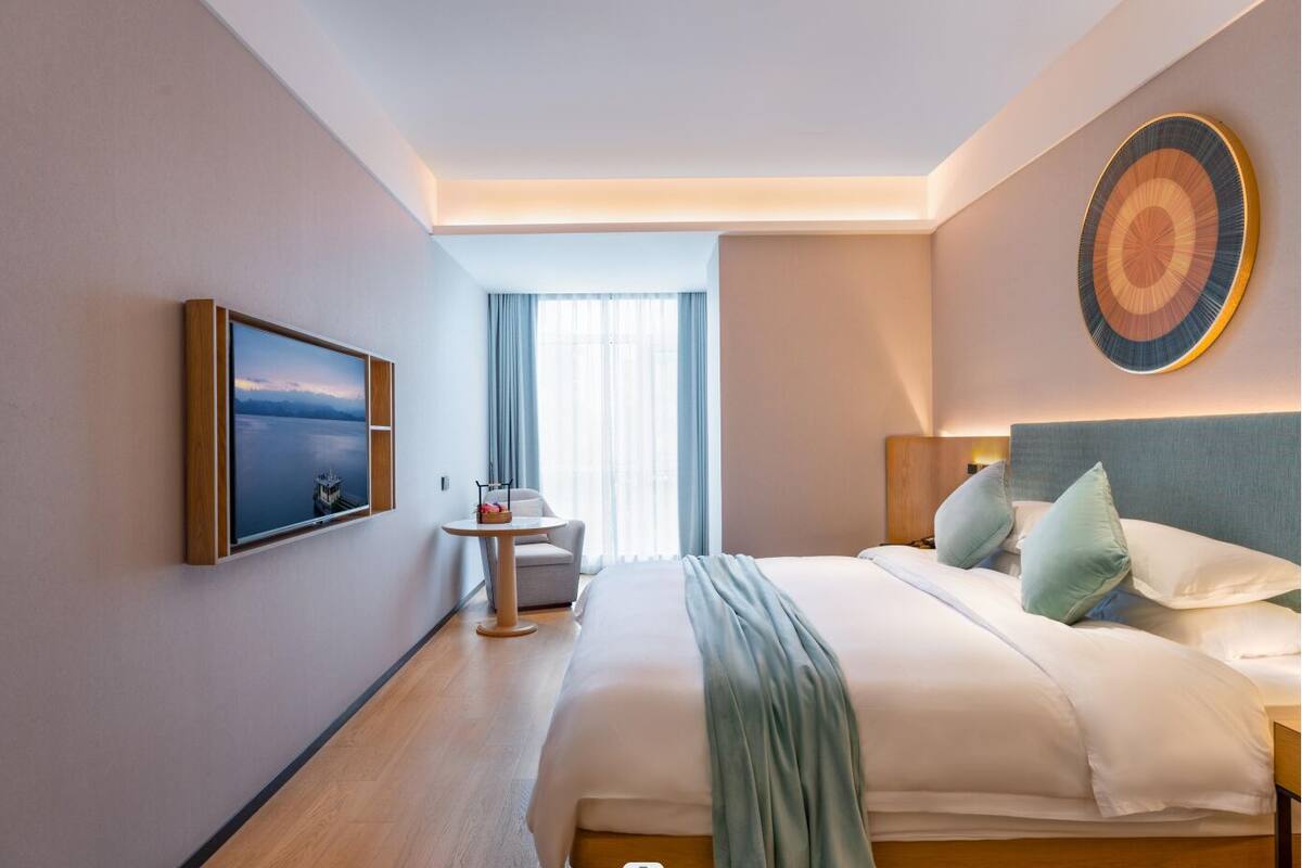 Habitación de hotel con cama, mesita de noche y televisor montado en la pared.