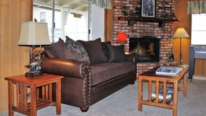 A cozy living room with a leather sofa, a small wooden table, and a fireplace. - Cabin with Foosball-Southern Comfort (Big Bear Lake)