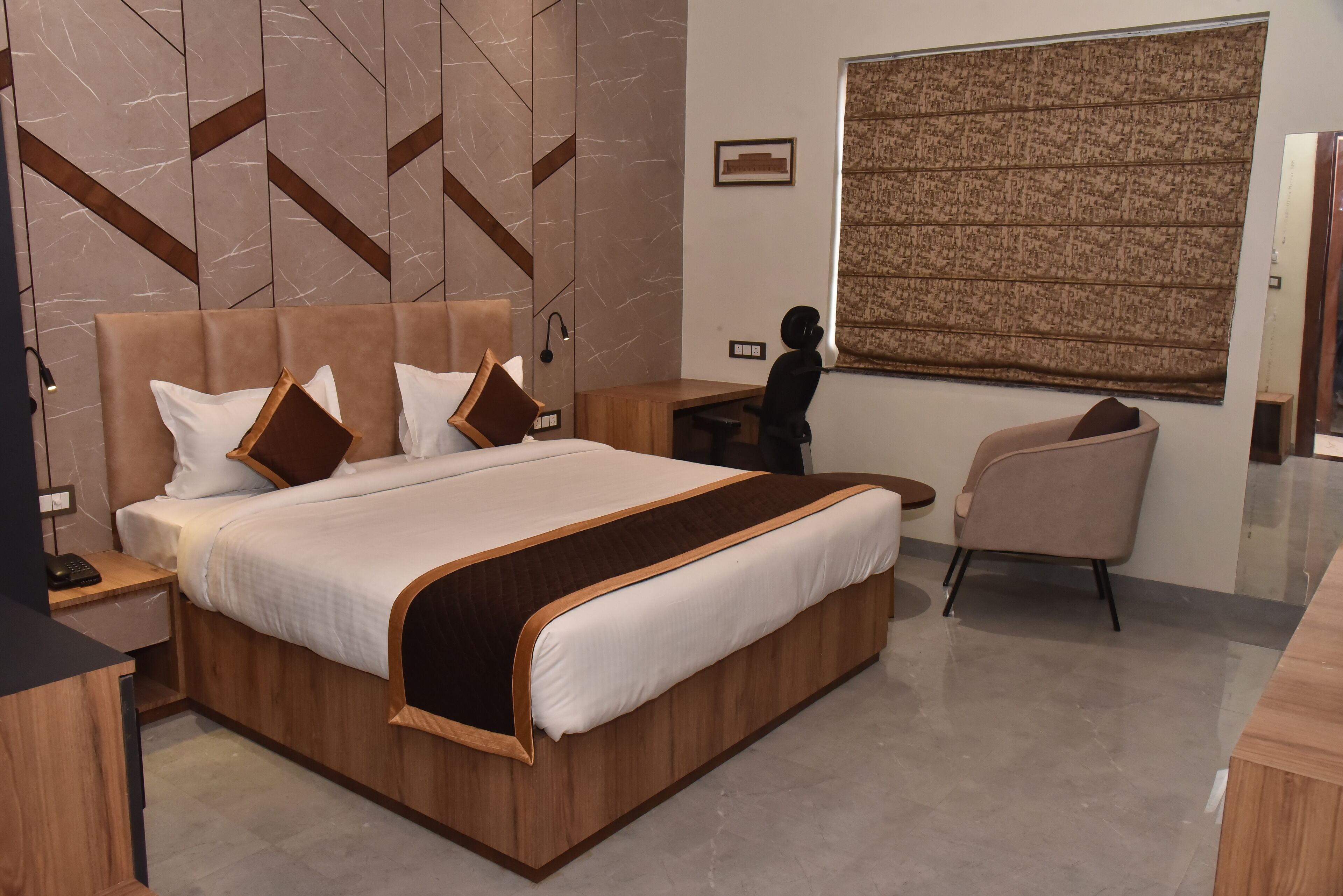 A modern hotel room with a large bed, a desk, and a chair.