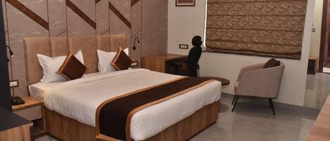 A modern hotel room with a large bed, a desk, and a chair.