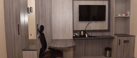 A modern room with a desk, chair, TV, and storage cabinets.