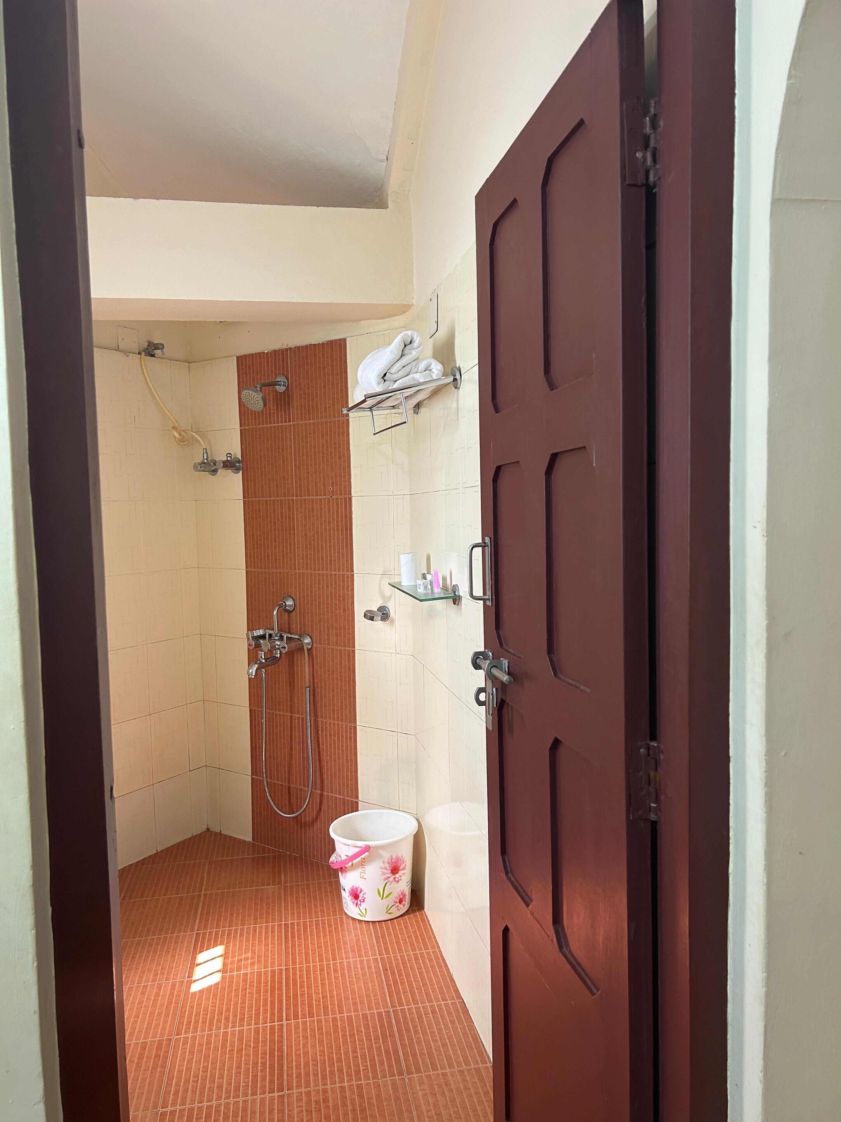 A small bathroom with a shower, a toilet, a sink, and a wooden door.