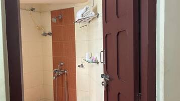 A small bathroom with a shower, a toilet, a sink, and a wooden door.