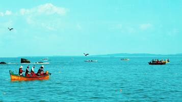 Mar tranquila con varios barcos, incluyendo un barco naranja destacado con gente a bordo.