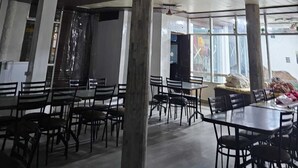 Une salle à manger spacieuse avec de hauts plafonds, des ventilateurs de plafond et de grandes fenêtres qui laissent entrer la lumière naturelle.