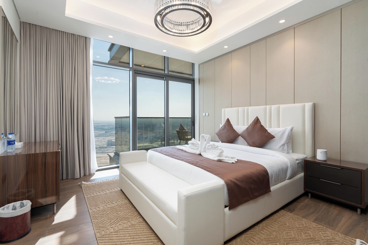 Une chambre d’hôtel moderne avec un grand lit, une table de chevet, une commode et une vue sur la ville.