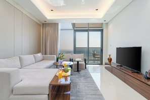 Ein modernes Wohnzimmer mit Sofa, Couchtisch und Fernseher. Ein Balkon bietet einen Ausblick.