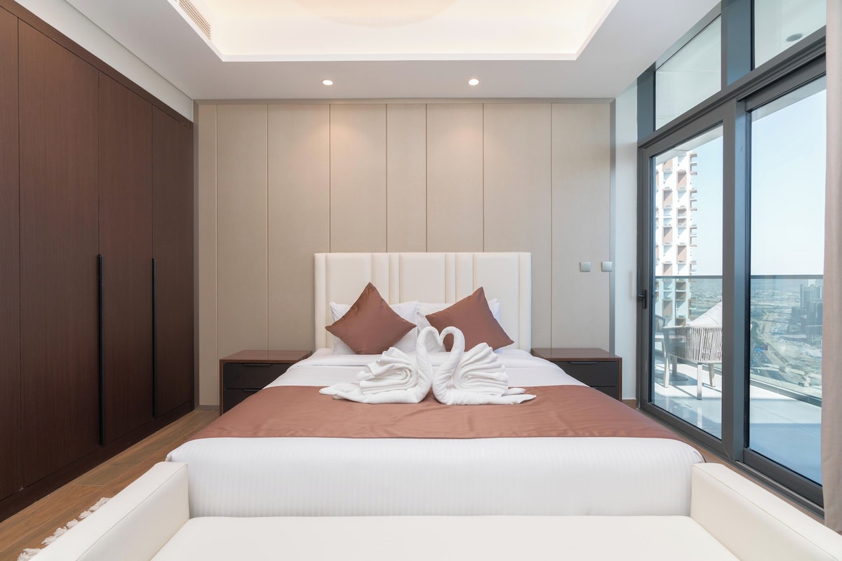 Ein modernes Hotelzimmer mit einem großen Bett, zwei Nachttischen, einem Kleiderschrank und einem Balkon mit Blick auf die Stadt.