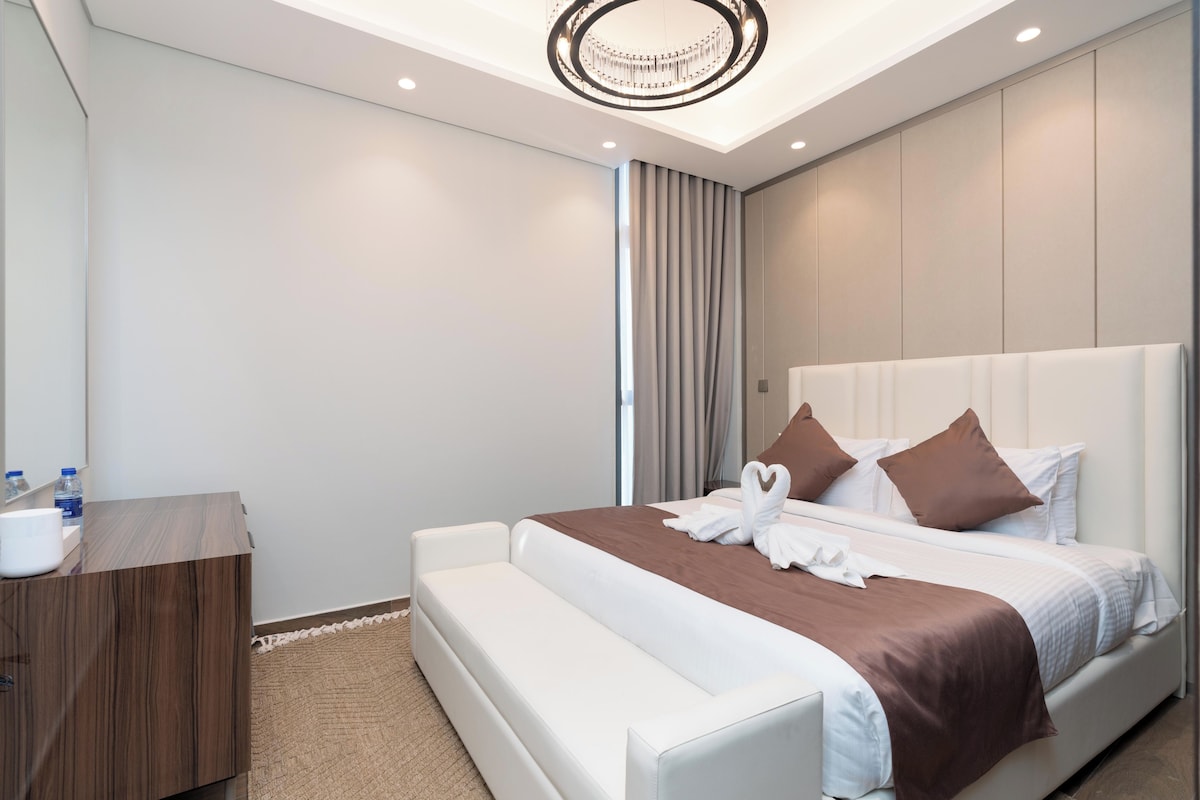 Ein modernes Hotelzimmer mit einem großen Bett, einem Nachttisch und einer Kristallleuchtre.