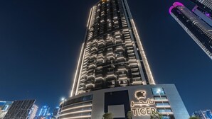 Un immeuble de grande hauteur doté de balcons illuminés et d’une enseigne bien visible sur laquelle on peut lire « TIGER ».