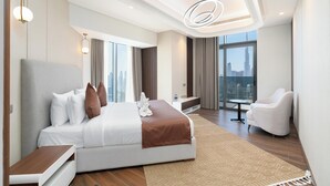 Une chambre d’hôtel moderne dotée d’un grand lit, d’un coin salon, d’une petite table et offrant une vue sur le paysage urbain.