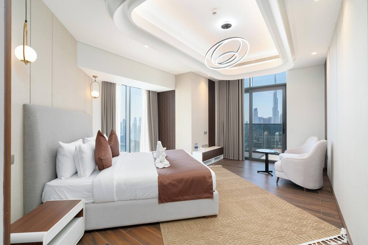 Habitación de hotel moderna con una cama grande, un rincón de descanso, una mesita y vistas a la ciudad.