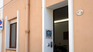A building entrance with a door, a sign, and a number plate. - Su Cerexinu | Authentic Sardinian hospitality between Cagliari and the sea (Selargius)