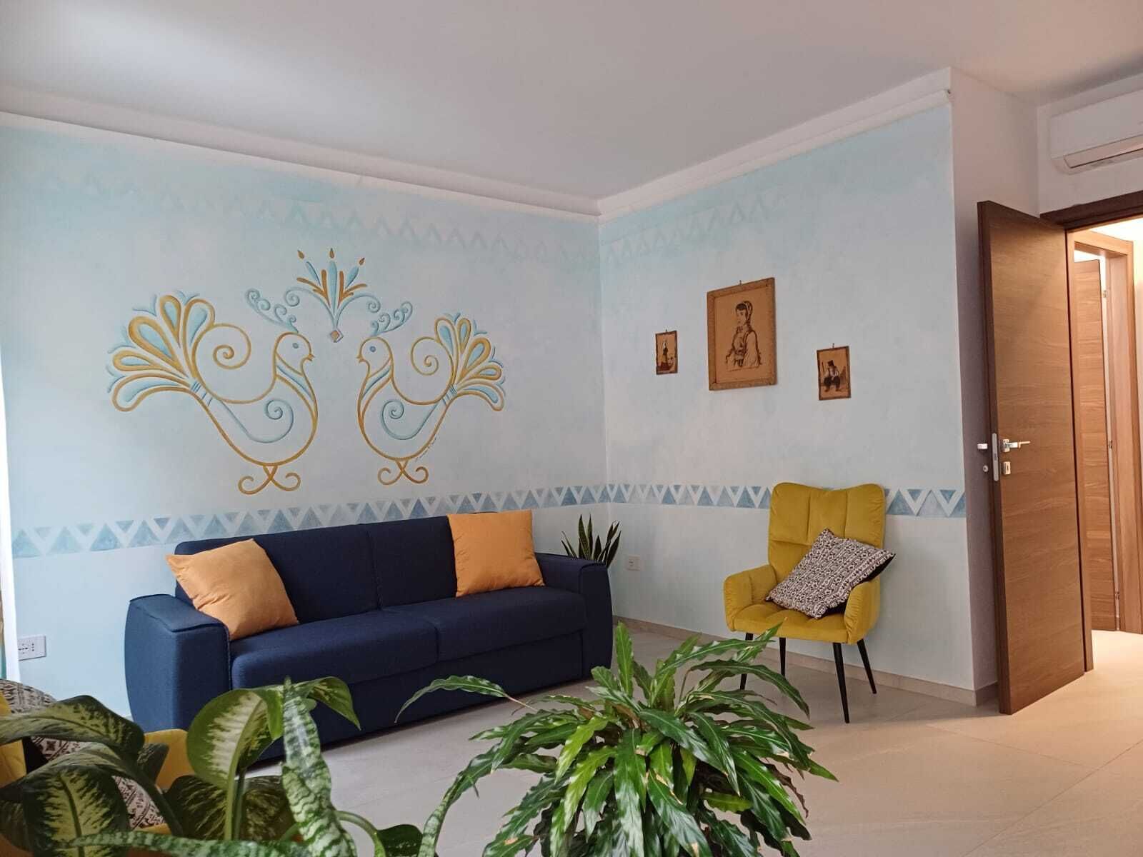 A living room with a dark blue sofa, yellow armchair, and green plants.