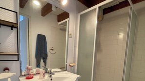 A bathroom with a white sink, mirror, and glass shower enclosure.