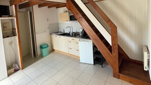 A spacious kitchen with a wooden staircase leading to an upper level.