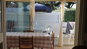 A dining area with a table set for four, surrounded by chairs, and a large umbrella providing shade.