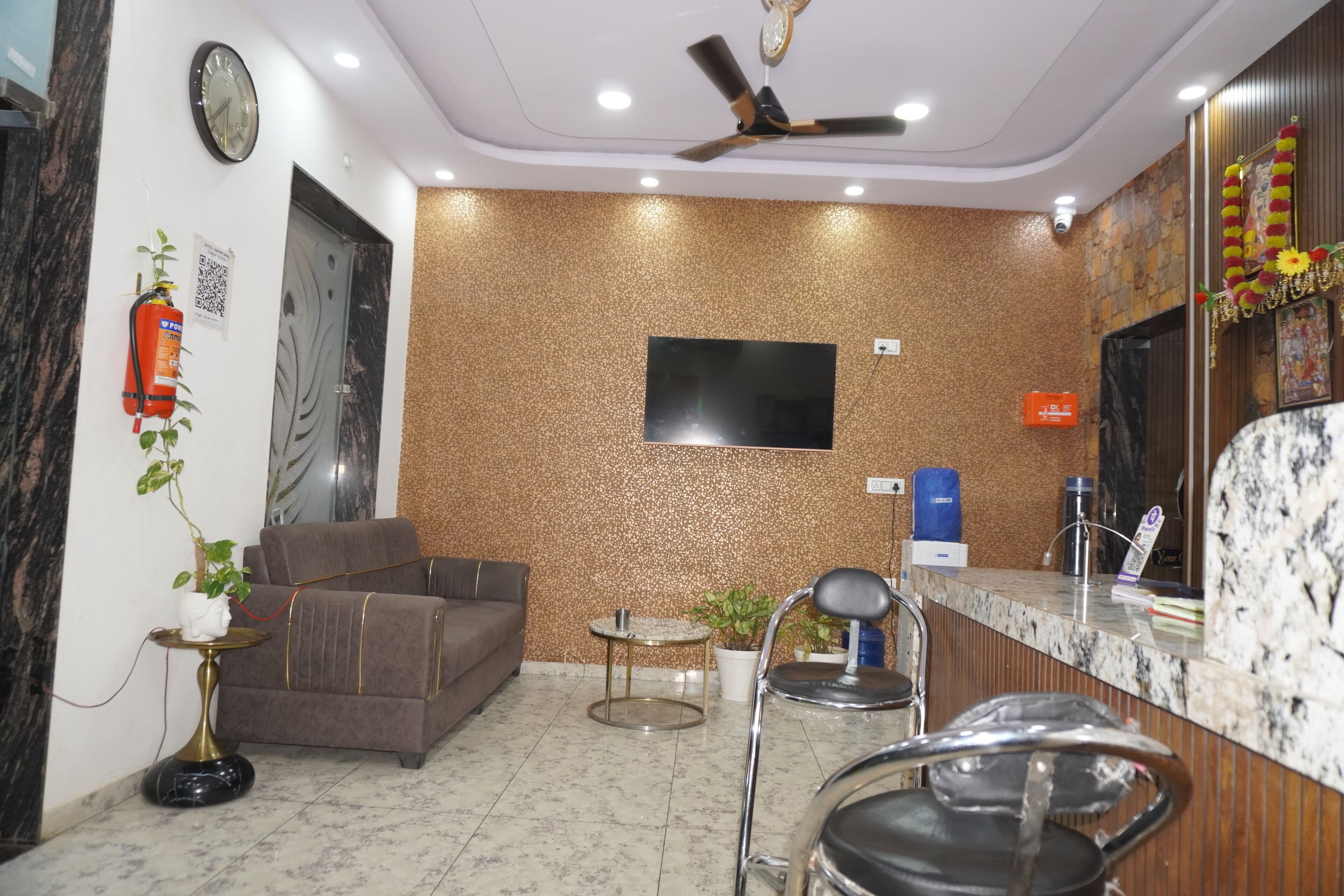 Un área de recepción moderna con un sofá, sillas, un televisor y una mesa de recepción.