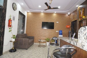 A modern reception area with a sofa, chairs, a television, and a reception desk.